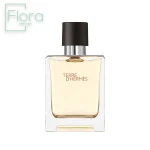 شیشه عطر مردانه تق د هرمس با طراحی ساده و شیک به تصویر کشیده شده است. شیشه شفاف با مایع درون آن کهربایی رنگ است و دربی به رنگ مشکی مات دارد. نام عطر “Terre d’Hermès” با فونتی ظریف روی شیشه حک شده است. لوگوی “Flora Perfume” نیز در گوشه بالا سمت چپ تصویر دیده میشود.