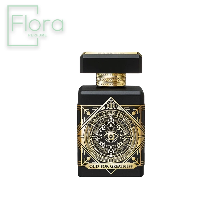 تصویر نمای نزدیک از بطری عطر Initio Oud for Greatness. بطری مشکی رنگ با طراحی هندسی و تزئینات طلایی است. در قسمت جلویی بطری، یک دایره طلایی با طرح چشم قرار دارد و در پایین آن عبارت “OUD FOR GREATNESS” نوشته شده است. درپوش بطری مشکی رنگ و مکعبی شکل است.